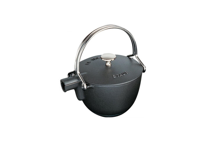 A dark, round cast iron teapot with a metal handle, reflecting a rustic aesthetic.