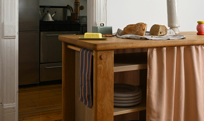A solid wood kitchen island with fresh bread and kitchen essentials in a warm, domestic setting.