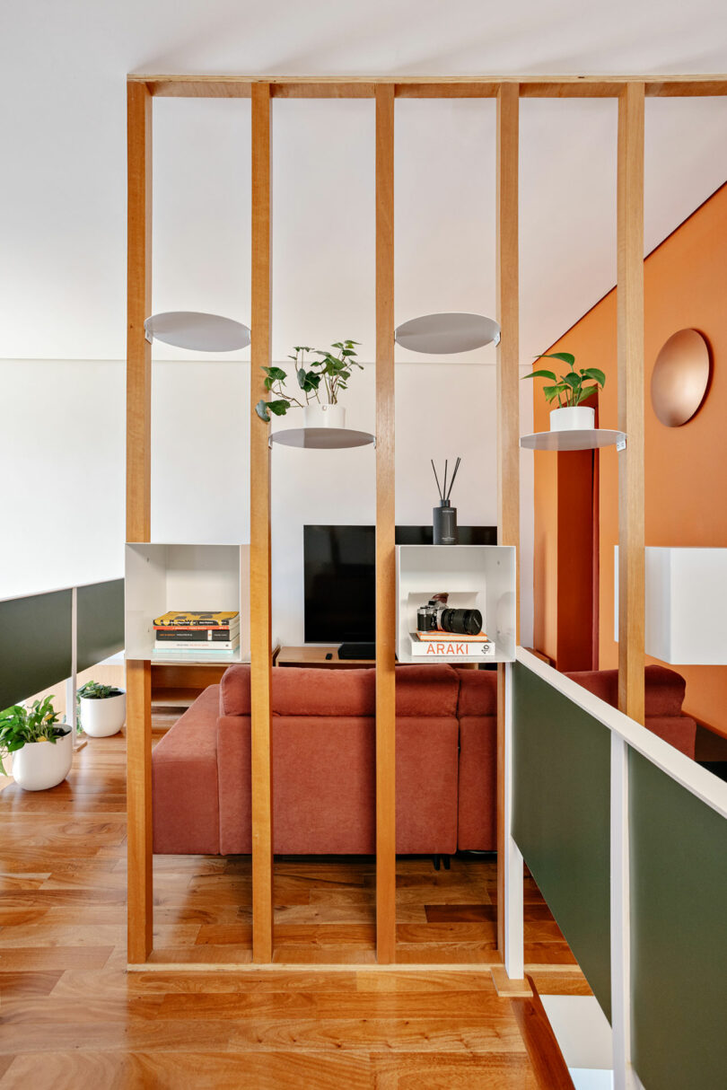 A wooden slat partition with integrated shelving in a modern living room.
