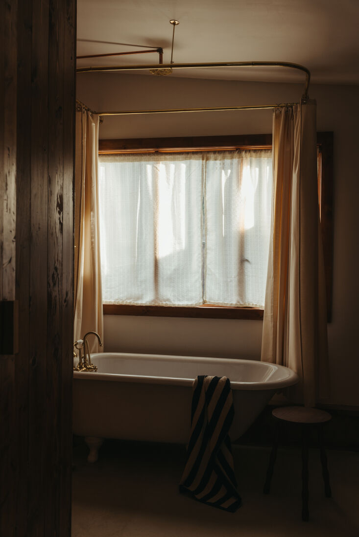 A restored white cast iron clawfoot tub in a cedar-walled bathroom.