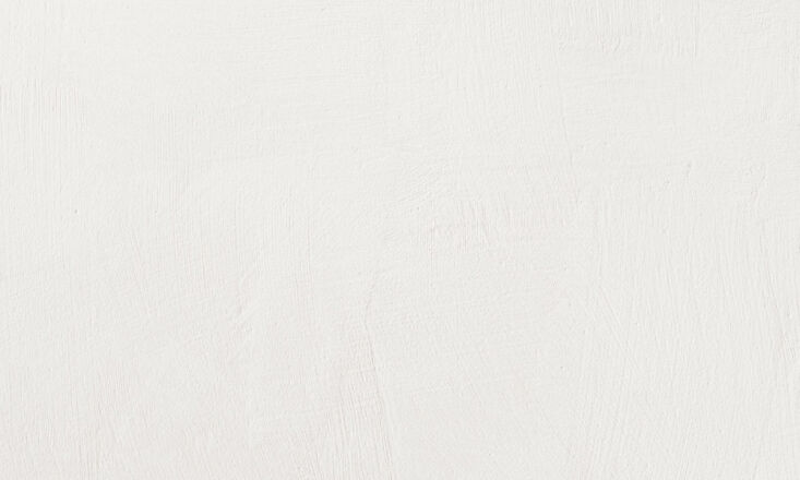 Close-up of a wall with a textured, matte gray lime-wash finish.