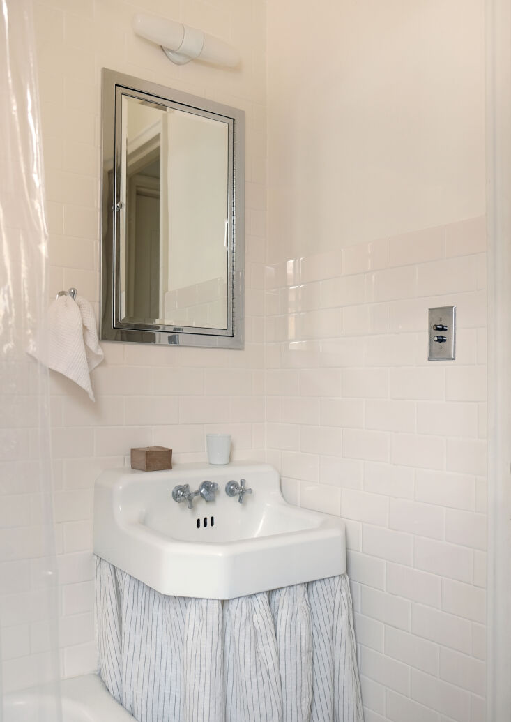 A striped duster-style sink skirt in a small bathroom with white subway tiles.