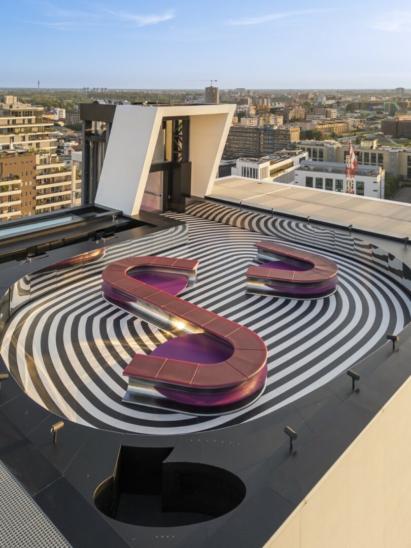 Two magenta modular benches forming an S-shape on a rooftop with city views.