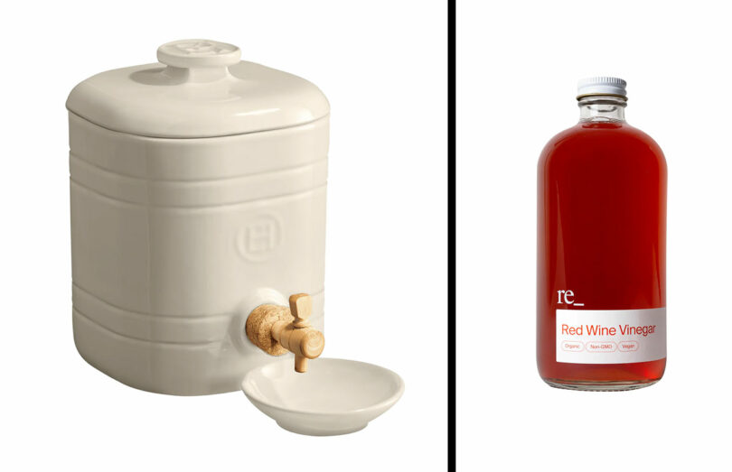 White ceramic vinegar crock with a wooden spigot placed next to a bottle of red wine vinegar.