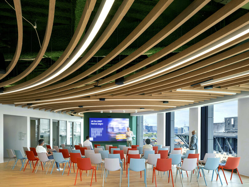 Modern conference room with LEGO-colored chairs and a wooden slat ceiling.