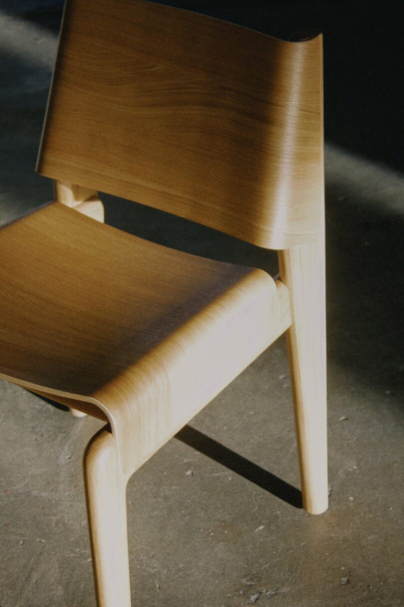 Side profile of the modern wooden chair showing the dramatic curvature of the seat and back.
