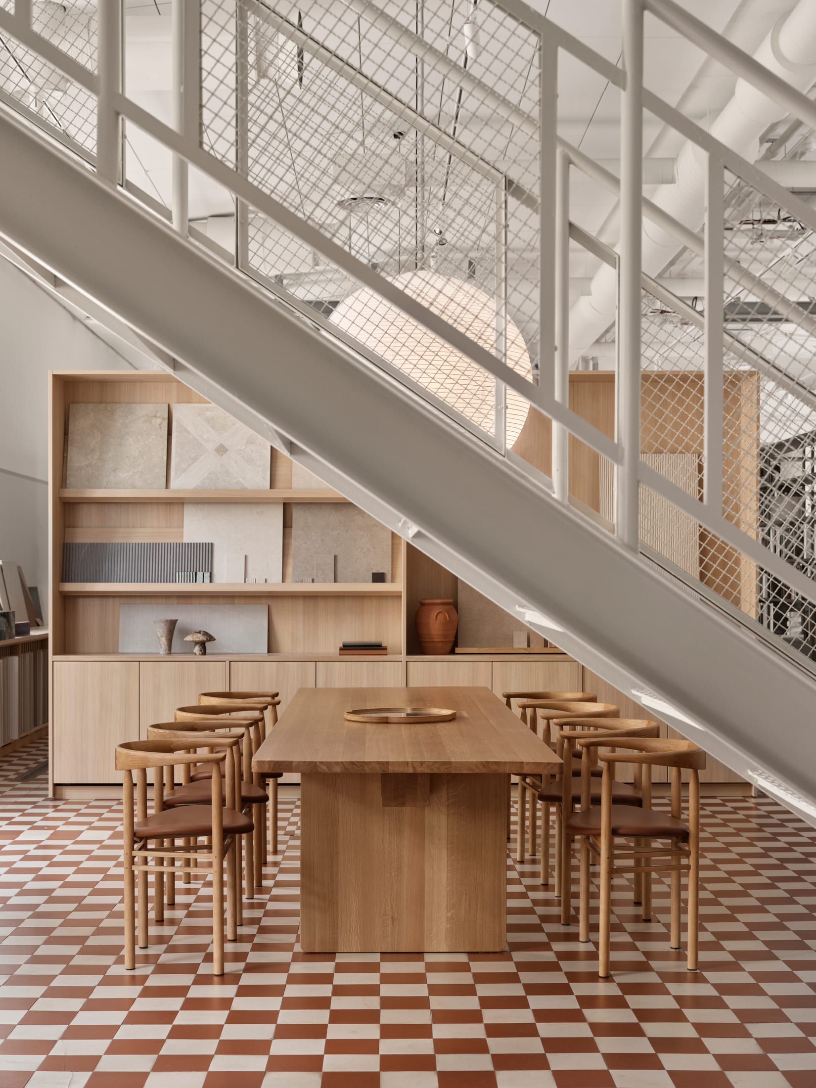 Interior of Fyra Studio featuring high windows and a large wooden communal table.