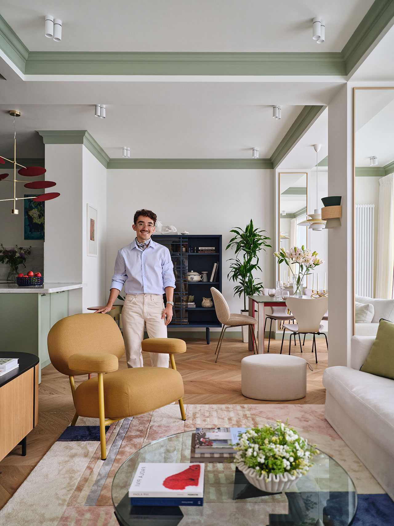 A man standing in a modern living space with green wall accents and contemporary furniture.