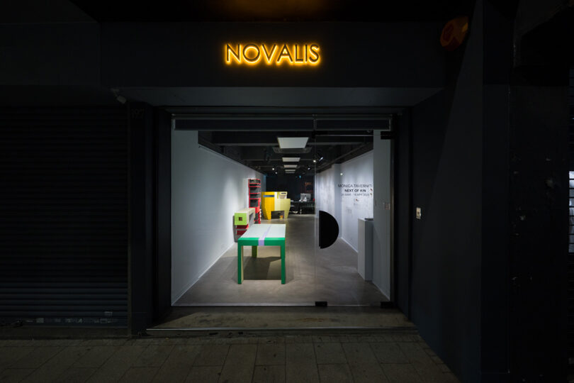 Exterior view of Novalis Art Design gallery in Hong Kong with neon signage and furniture window display.