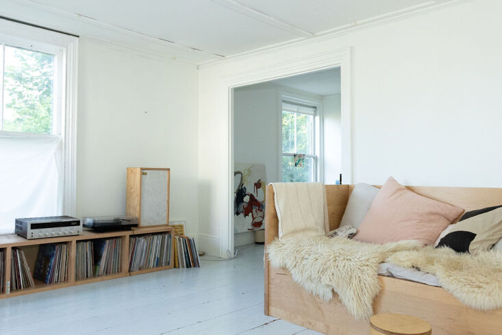 A minimalist wooden daybed and record case in a bright living room.