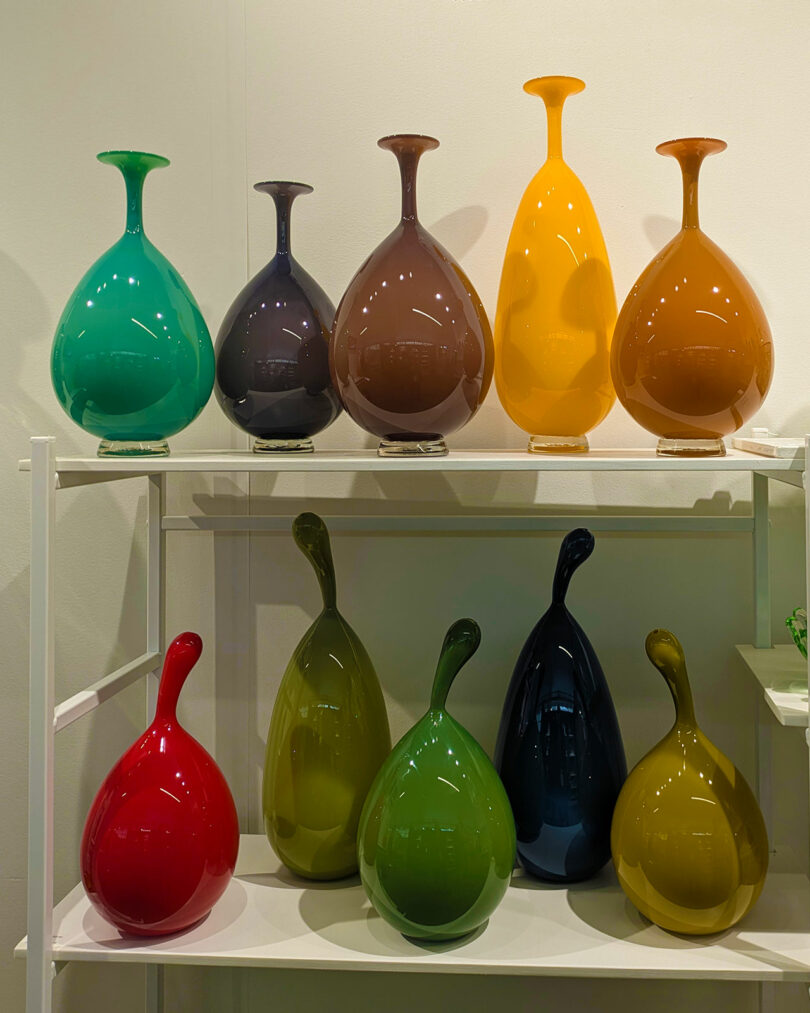 Shelves of colorful, glossy ceramic vases in red, blue, yellow, and green.