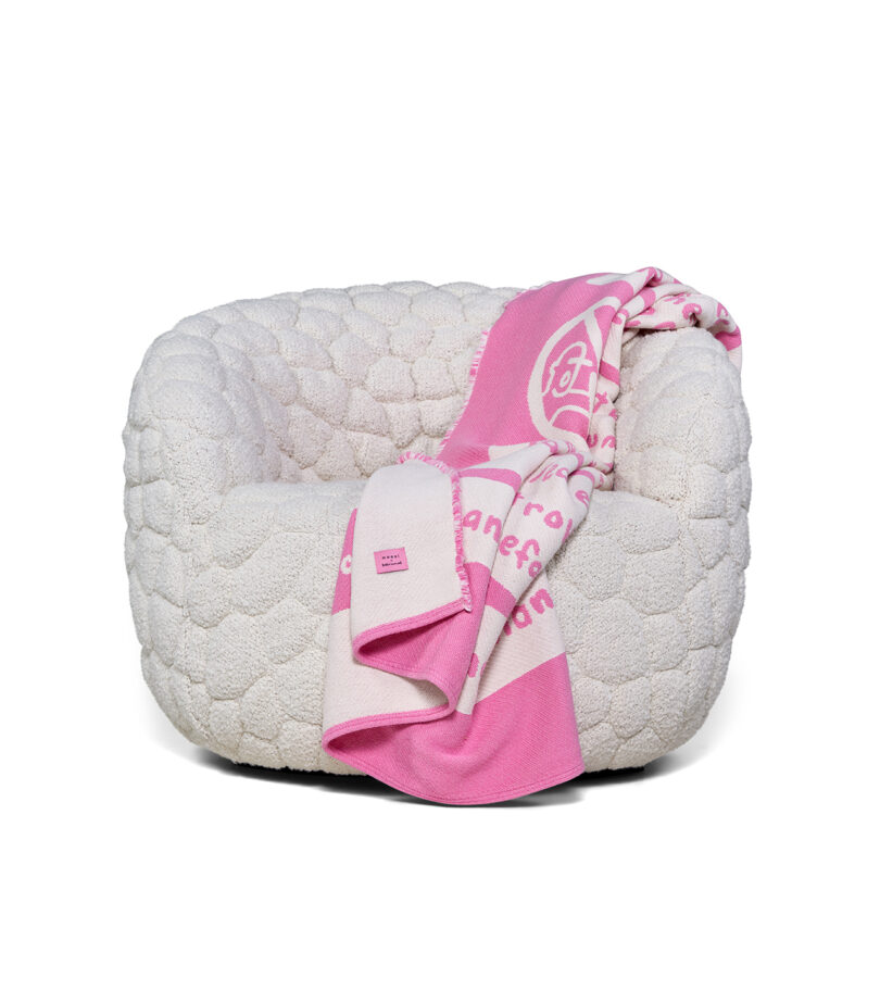 The white textured Introvert Chair with a pink and white patterned security blanket draped over the side.