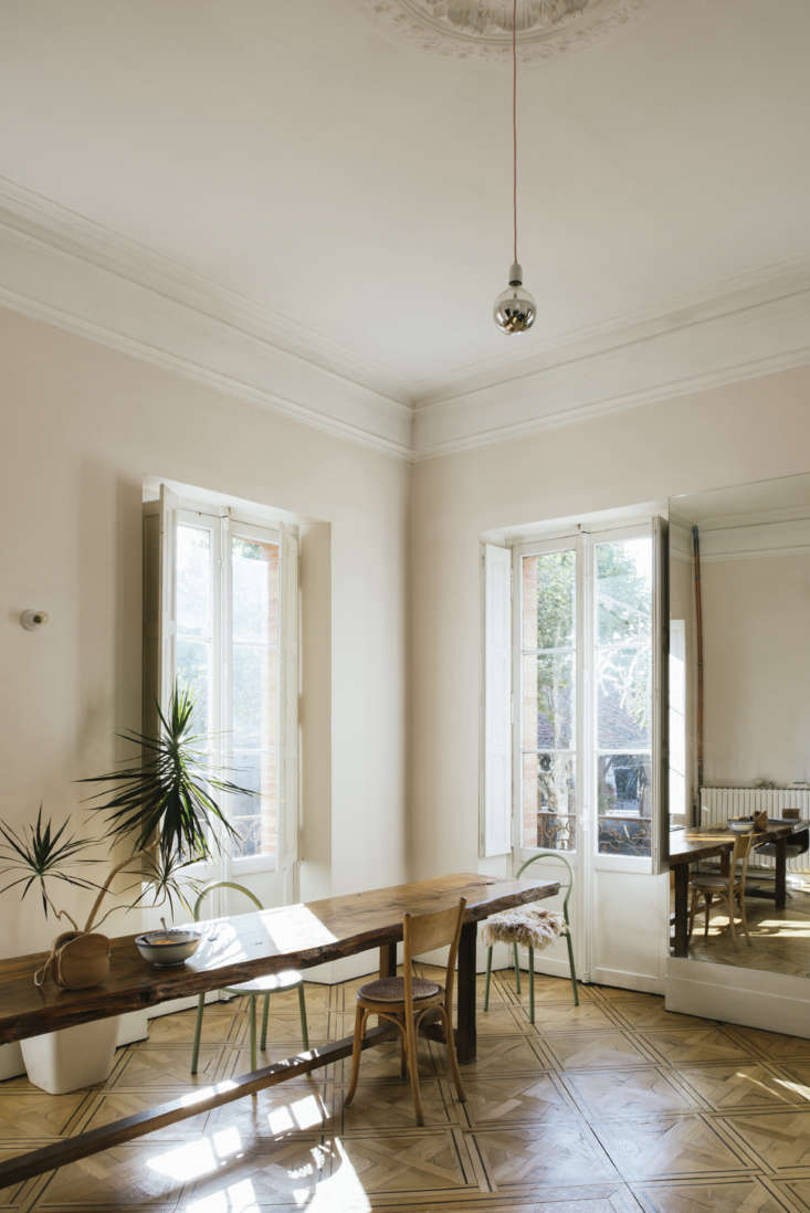 A single silver-tipped bulb hanging as a pendant in a minimalist French interior.