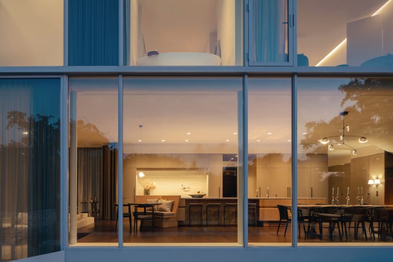 Night view of the modern glass addition showing the warmly lit dining and living areas inside.