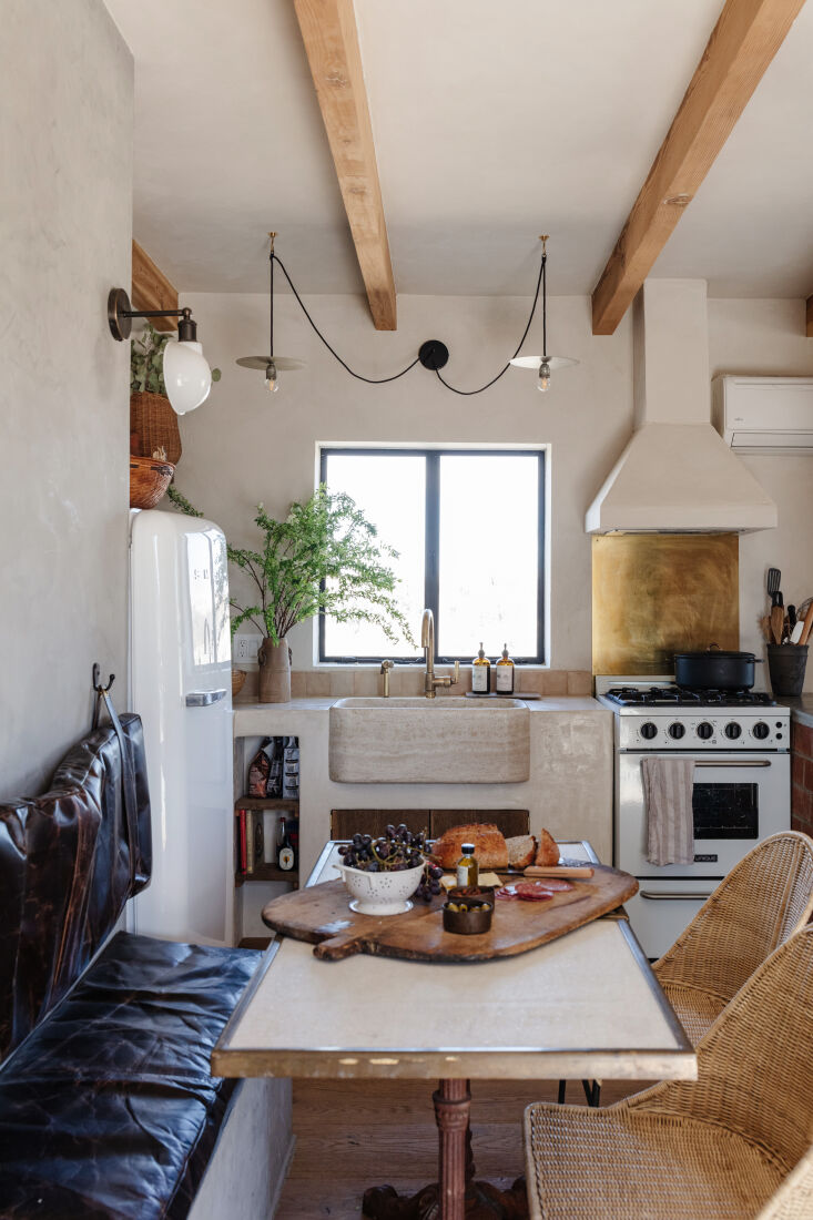 A kitchen stove area featuring a backsplash made of repurposed tiles and a custom brass sheet.