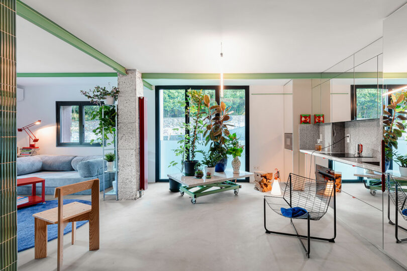 A sun-drenched living room with a blue sofa, various plants, and large windows.