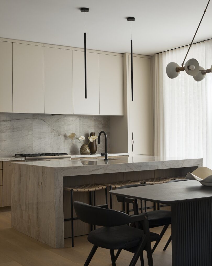 Modern kitchen with marble countertops, black fixtures, and dark wooden furniture.