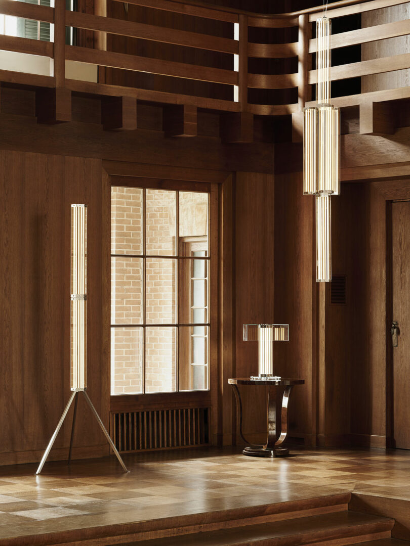 A wood-paneled room displaying modern vertical light fixtures on a tripod stand, ceiling, and table.