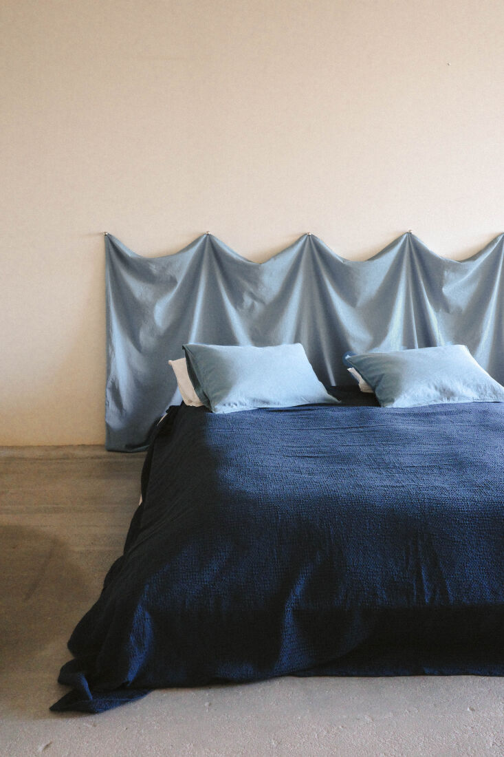 Tonal blue bedding featuring a fabric headboard, coverlet, and hemp-cotton pillowcases.