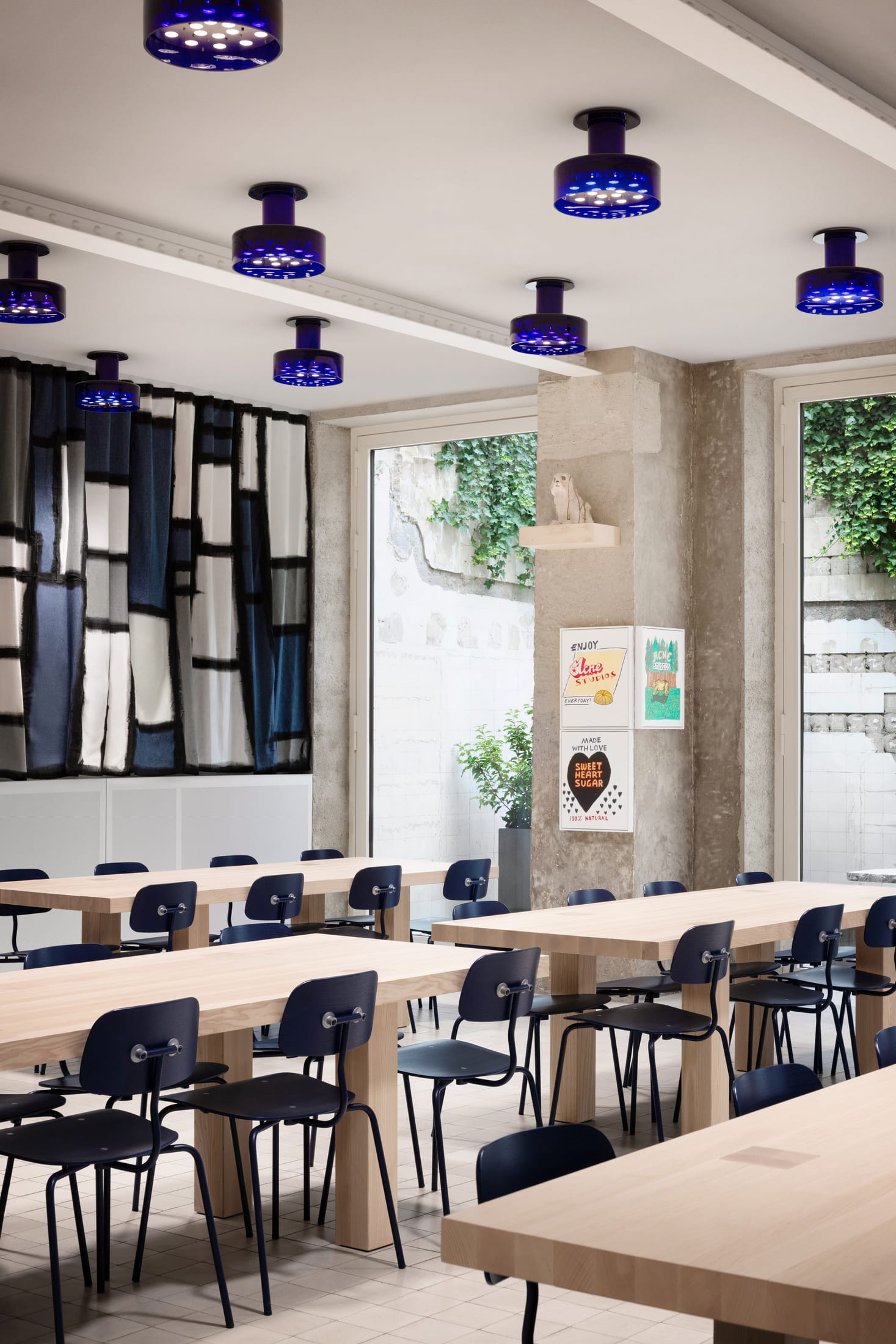 The canteen area of Acne Studios Paris HQ featuring inky blue walls and stainless steel surfaces.