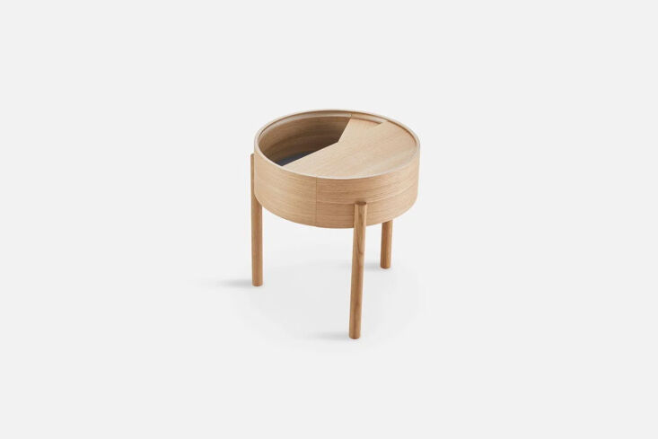 A circular oiled oak side table with a lid that slides to reveal storage.