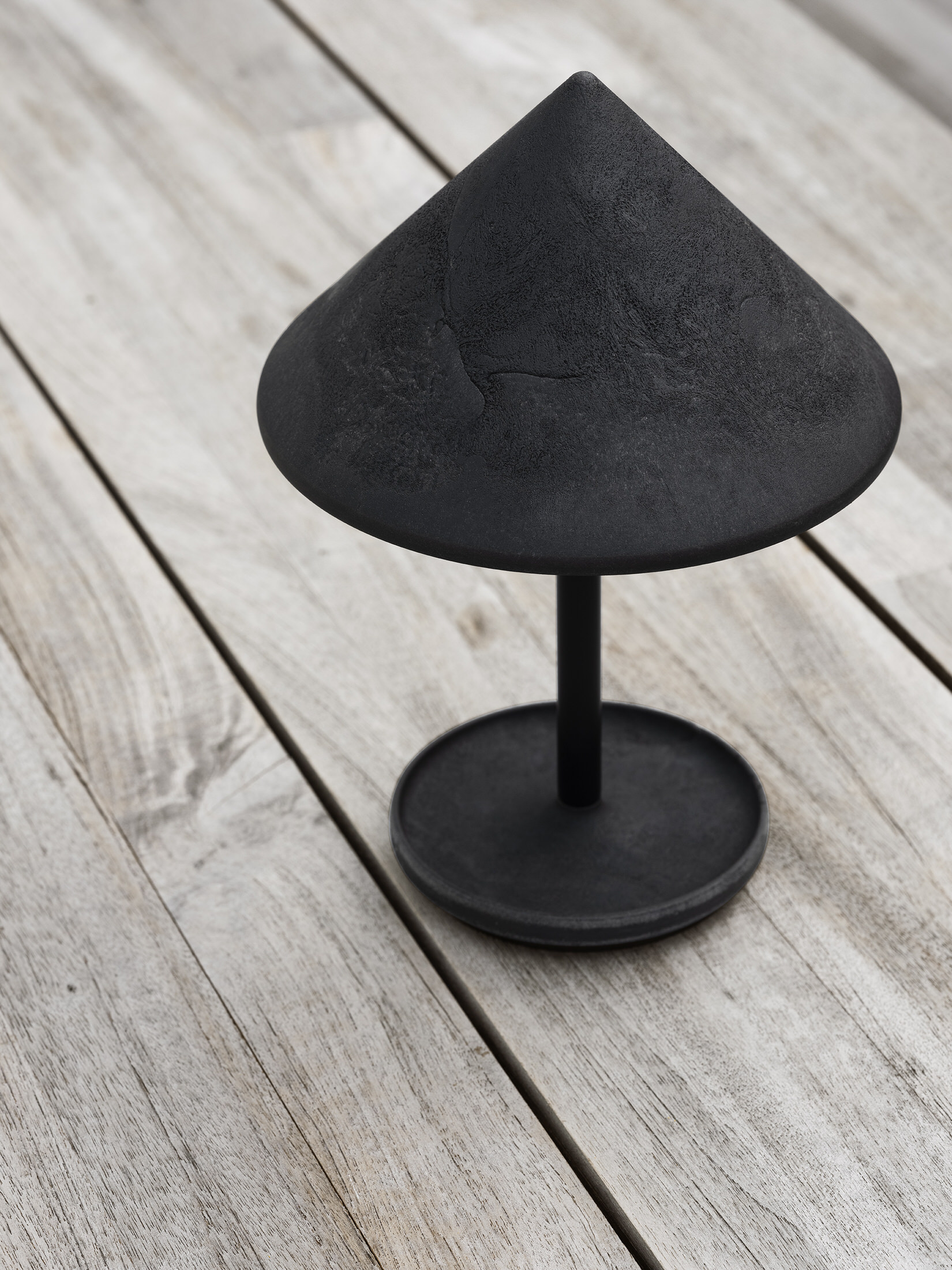 The Mater Terra portable lamp on a bedside shelf, casting a warm glow.