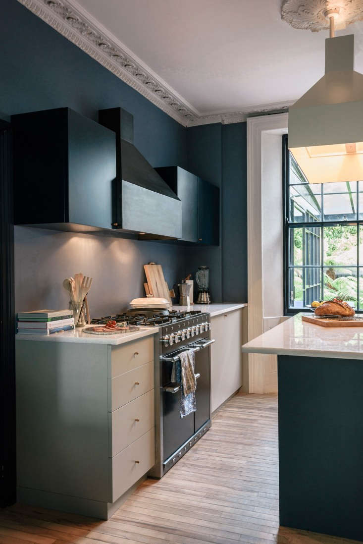 Close-up of a sculptural blackened steel kitchen hood and upper cabinets painted in dark Basalt blue-black.