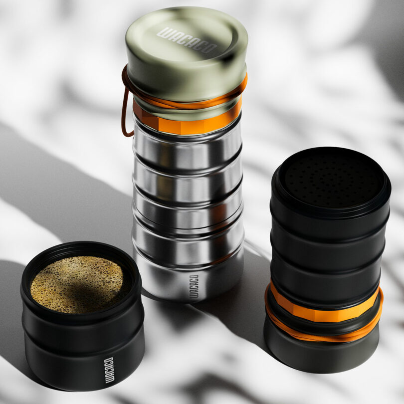 Three stainless steel coffee brewing containers with orange accents, one showing freshly ground coffee inside.