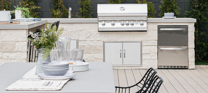 A close-up of a stainless steel outdoor cooking station with a professional grill and cooling unit.