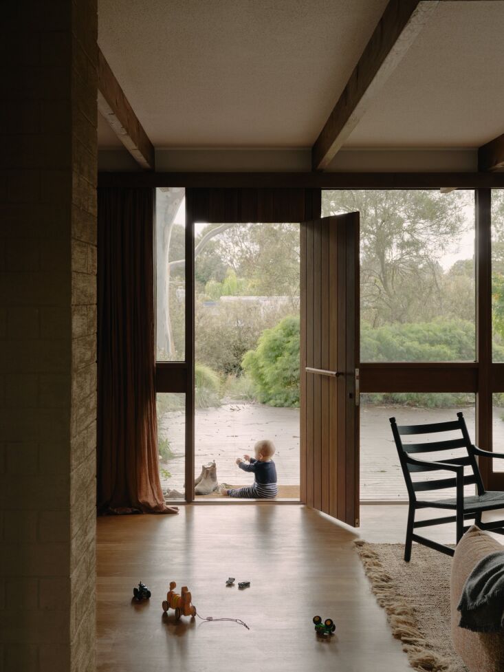 Child playing near an open front door that connects the living room directly to the outdoor yard.