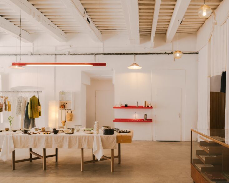 Red metal neon pendant lights hanging from the ceiling near lacquered red shelves.