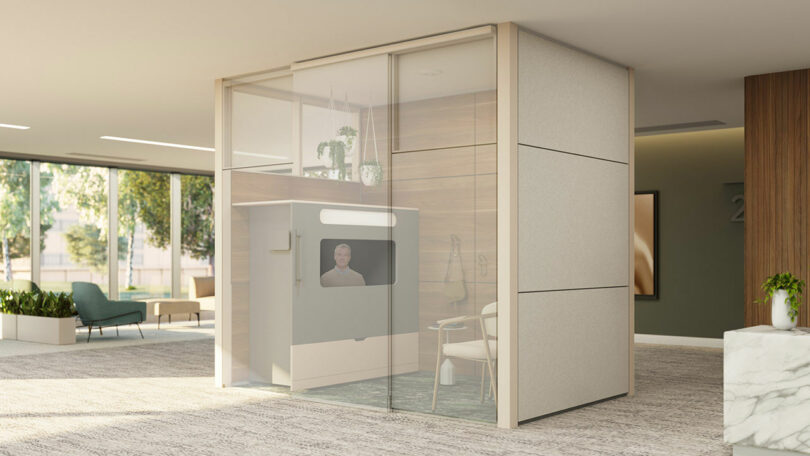 An exterior view of a modular privacy pod with glass walls in a well-lit office setting.