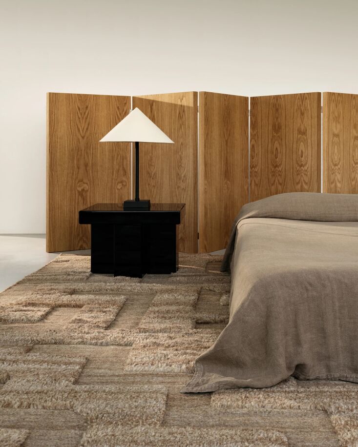 A boho-style bedroom featuring a light wood folding screen headboard and a Nordic Knots rug.