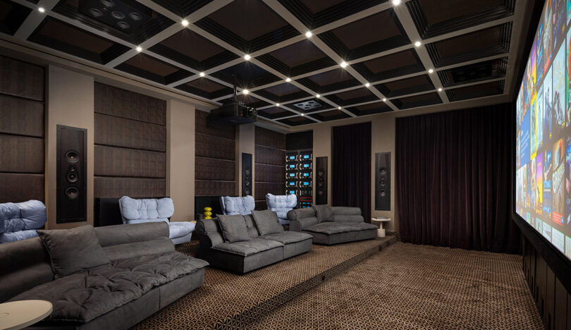 A luxury home theater with plush seating and integrated wall speakers.