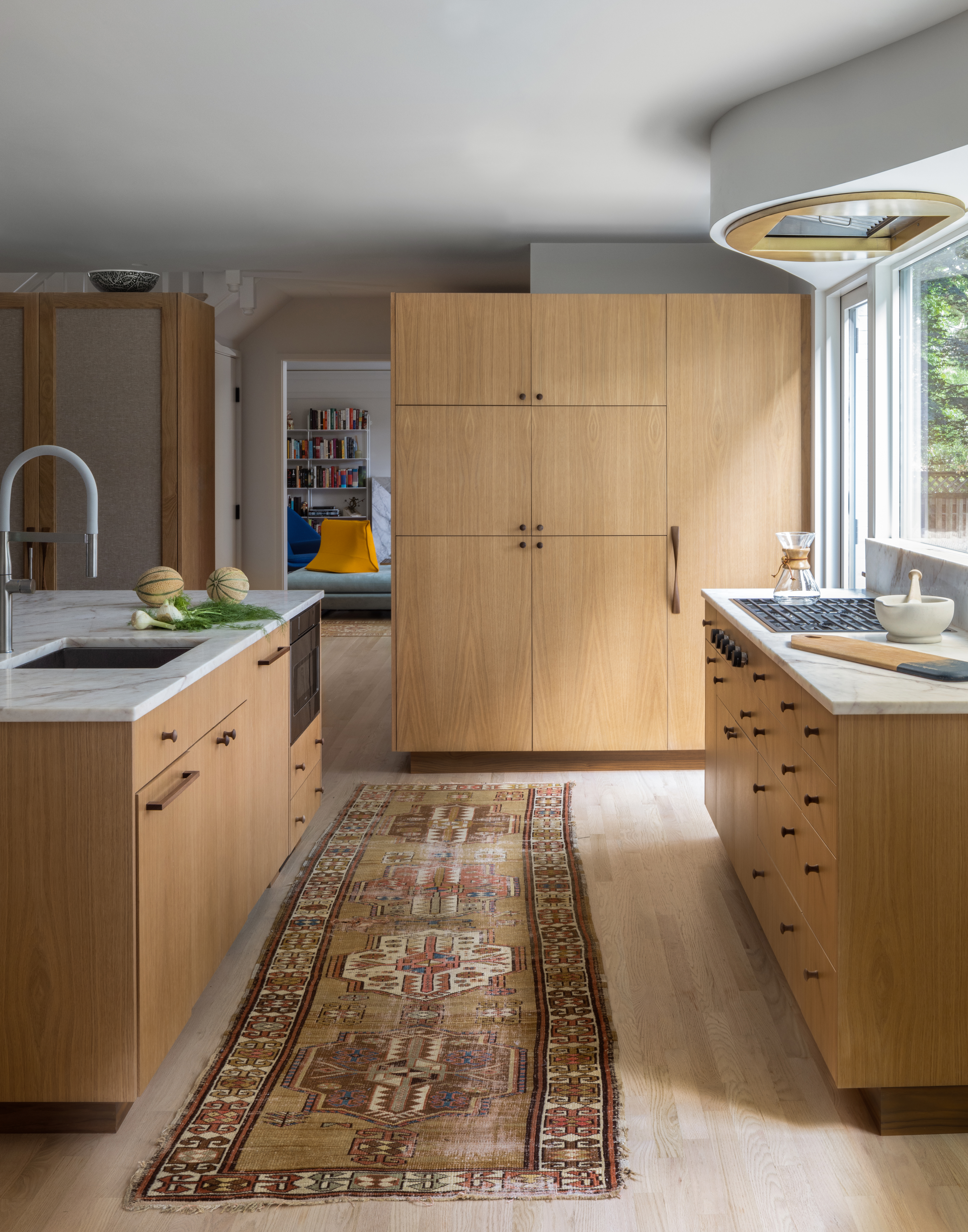 Custom white oak cabinets acting as room dividers, stopping short of the ceiling to allow light through.