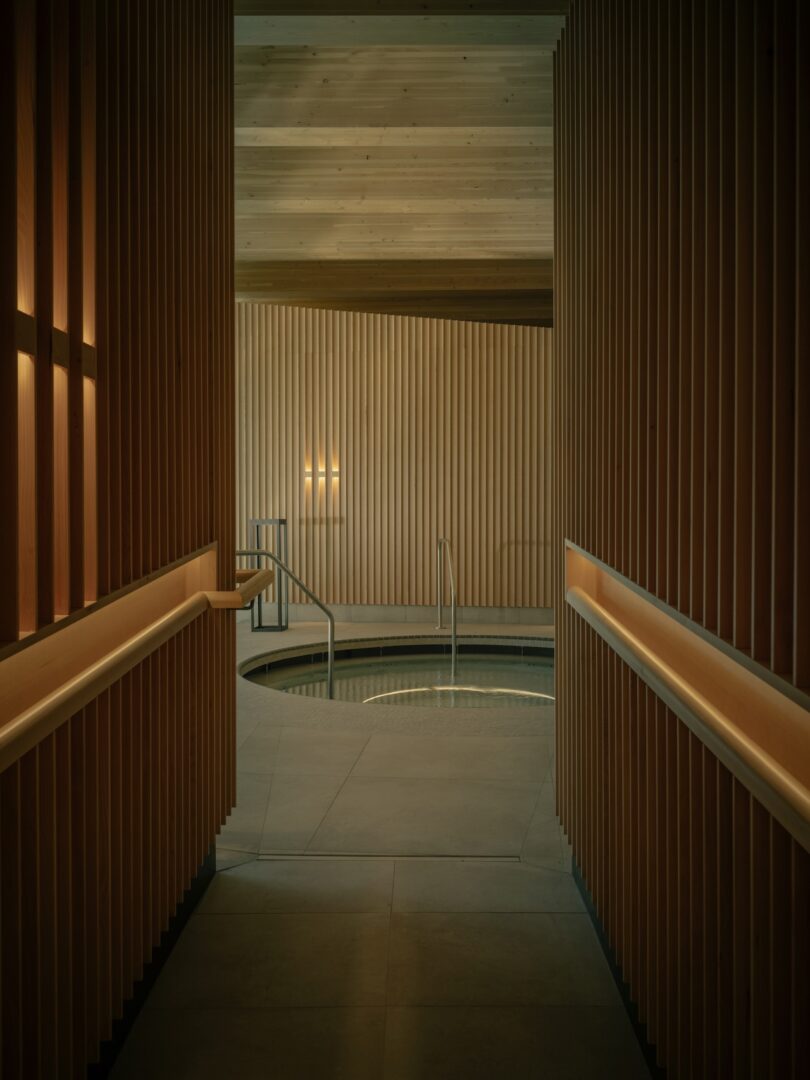A small circular indoor thermal pool surrounded by warm wooden paneling and soft lighting.