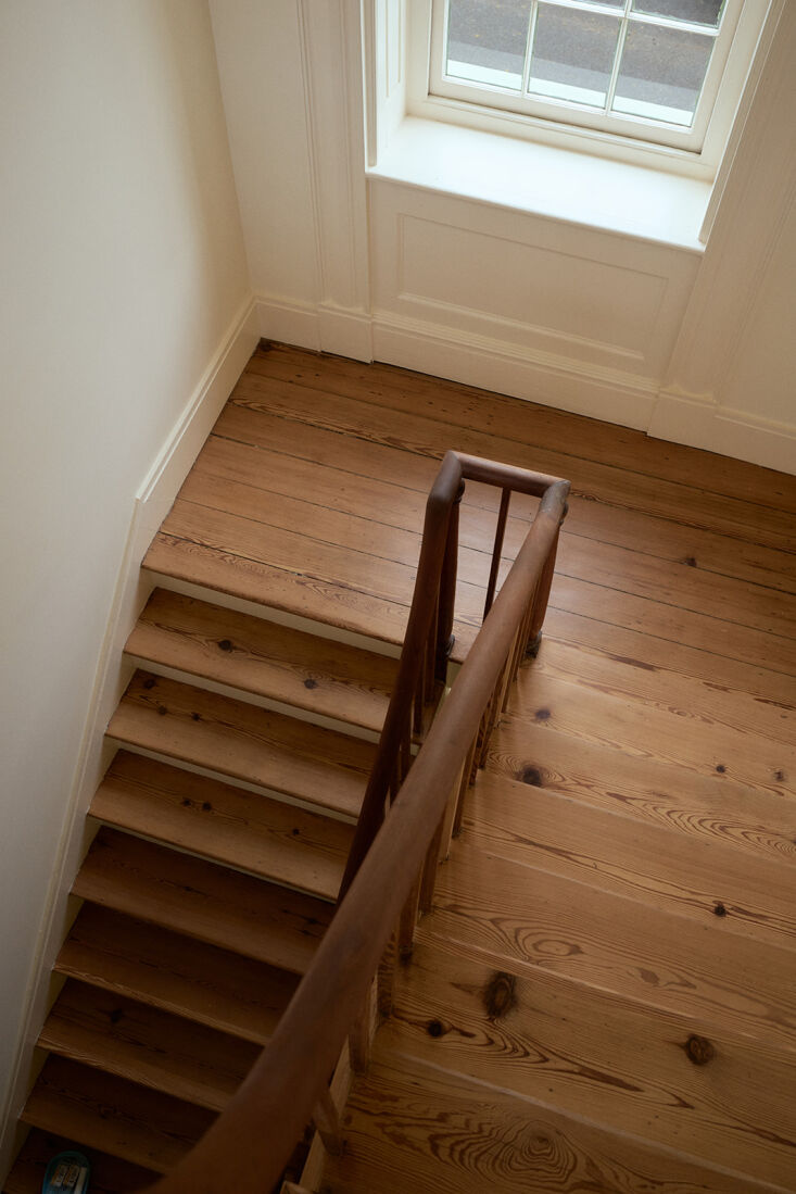 A graceful white stairwell with detailed molding and a warm wooden handrail.
