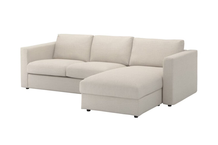 The beige IKEA Finnala sectional sofa with the chaise seat lifted to reveal a large internal storage compartment.