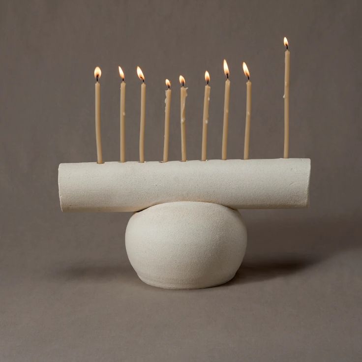 A white ceramic menorah with a detachable base that serves as a decorative vase.