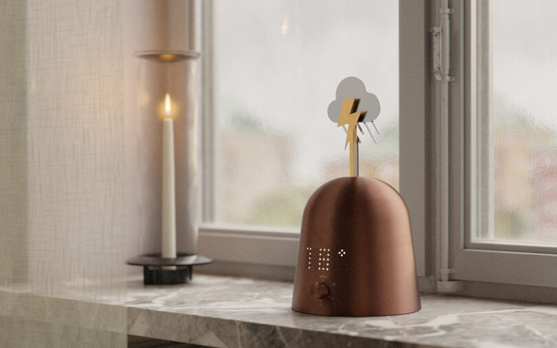 A Skymill device with a lightning symbol on a marble windowsill next to a lit candle.