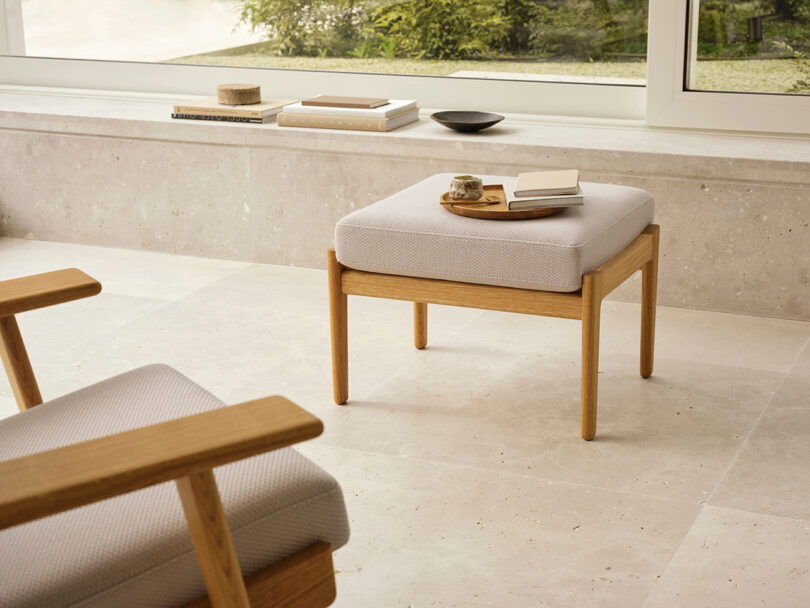 A CH290 ottoman used as a side table with a cup of coffee and a notebook near a window.