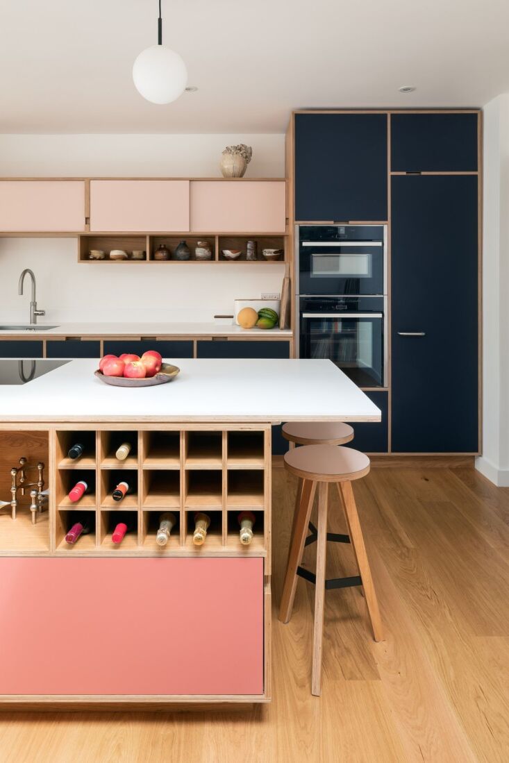 A built-in wooden bottle rack integrated into a colorful kitchen island.