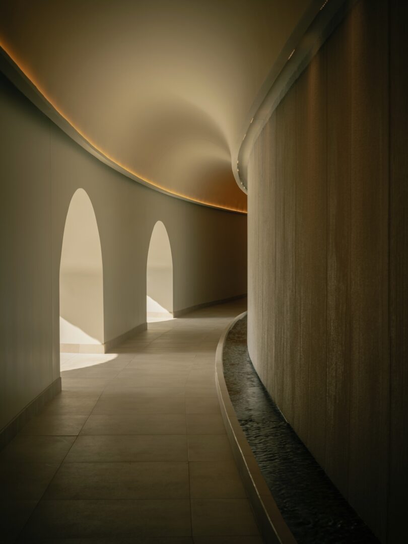 A curved indoor hallway with soft lighting and arched architectural openings.