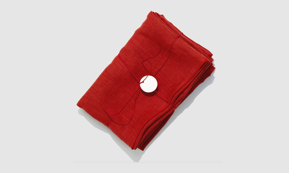 A set of red Tomato colored linen pillowcases on a bed.