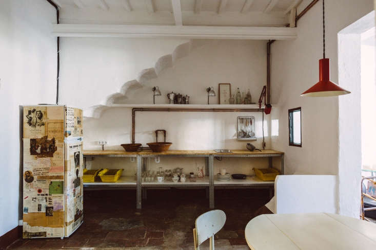 An industrial-style kitchenette featuring exposed copper piping and modular steel shelving in a top-floor apartment.
