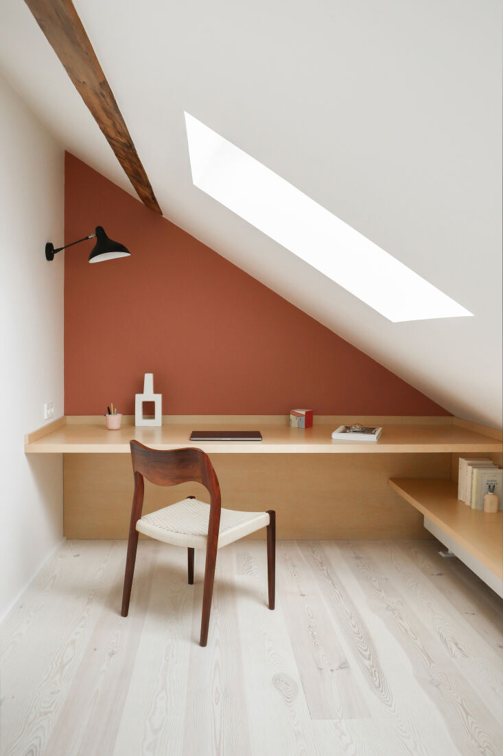 Built-in wooden desk area under the attic eaves with a vintage Niels Otto Moller chair.
