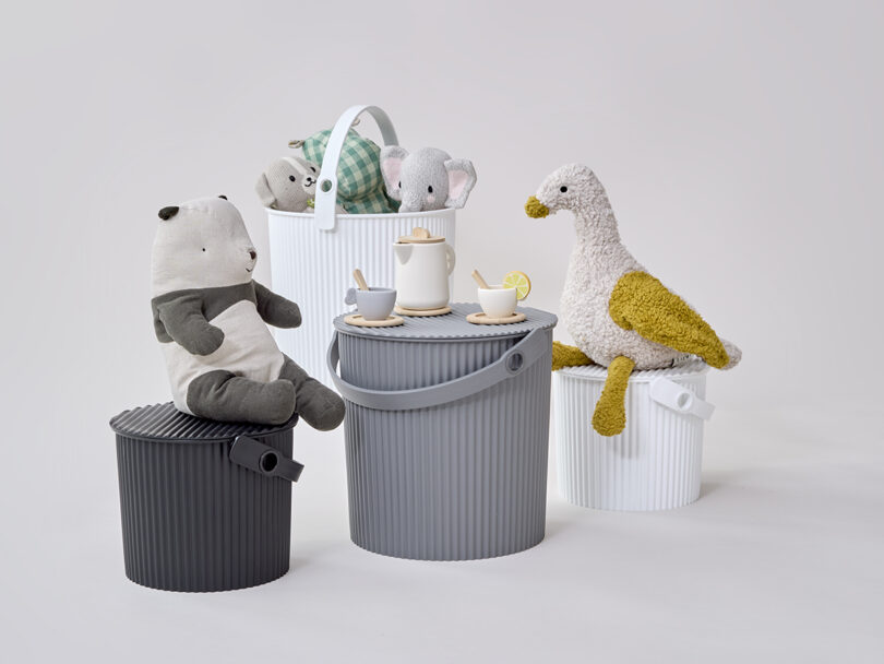 Stuffed animals sitting on top of several ribbed Hachiman storage buckets.