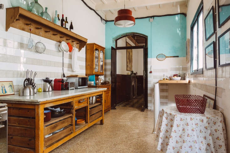 A vintage wooden counter with a marble top used as a kitchen island.