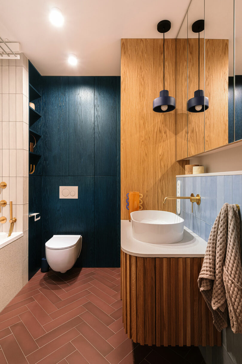 Modern bathroom featuring dark blue paneling, wood accents, and gold fixtures with a vessel sink.