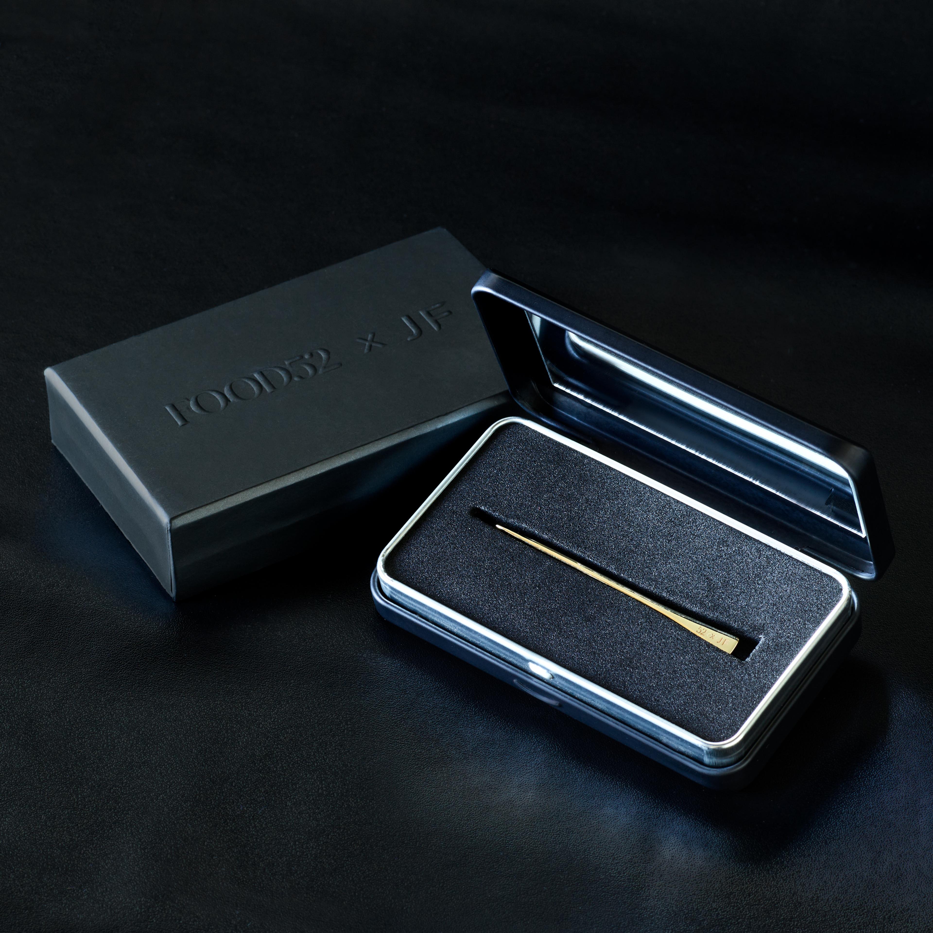 A gold toothpick tucked into a custom metal carrying case featuring an integrated mirror.